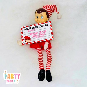 Op de afbeelding: Een rood-wit gestreepte elfpop die een wit briefje vasthoudt met de tekst "A note from your elf Billy Please keep your room clean!"