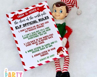 May include: A white card with red and white stripes on the edges. The card has a list of rules for elves, titled "Elf Official Rules". The rules are: 1. Don't touch me or I will lose my magical powers. 2. I can't talk but I'm a very good listener and can hear everything you say. 3. I go back to the North Pole every night to report back to Santa. 4. Write letters to Santa and I'll deliver them to him. 5. Always listen to your parents. 6. Always be kind! A toy elf is holding the card.