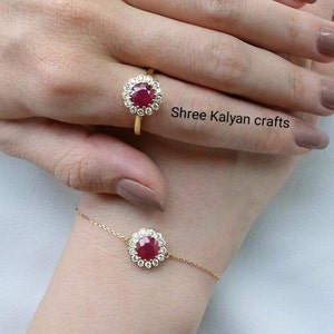 May include: A gold ring and bracelet set featuring a central ruby gemstone surrounded by a halo of smaller, clear stones. The ring is on a finger, and the bracelet is on a wrist. The text "Shree Kalyan crafts" is visible.