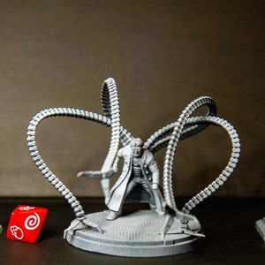 Peut inclure: Une figurine miniature en plastique gris de Doctor Octopus, un super-vilain de Marvel Comics, avec quatre tentacules mécaniques. La figurine est debout sur une base grise. Il y a un dé rouge avec un motif de spirale blanche au premier plan.