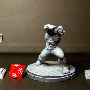 May include: A gray plastic miniature figure of the Hulk in a fighting pose, standing on a gray plastic base. The figure is surrounded by three gray plastic miniature street props: a traffic light, a street lamp, and a lamp post.