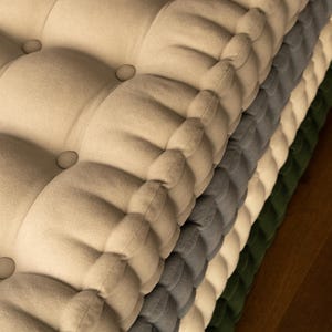 Peut inclure: Une pile de coussins touffet&eacute;s de diff&eacute;rentes couleurs : beige, gris, blanc et vert. Chaque coussin a un design boutonn&eacute;. Les coussins sont faits d'un tissu doux et textur&eacute;, et sont empil&eacute;s les uns sur les autres.