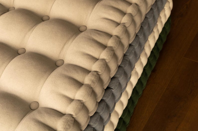 Peut inclure: Une pile de coussins touffet&eacute;s de diff&eacute;rentes couleurs : beige, gris, blanc et vert. Chaque coussin a un design boutonn&eacute;. Les coussins sont faits d'un tissu doux et textur&eacute;, et sont empil&eacute;s les uns sur les autres.
