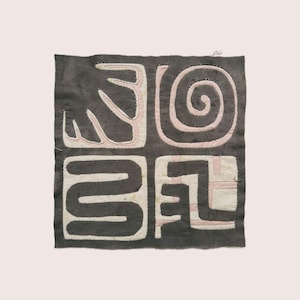 Op de afbeelding: Vierkant textiel met een donkergrijze achtergrond en vier verschillende secties. Elke sectie heeft een uniek abstract ontwerp in wit en lichtroze, waaronder een spiraal en gebogen lijnen. Het textiel is waarschijnlijk handgemaakt.
