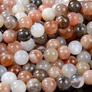 May include: A strand of round, smooth, sunstone beads in shades of white, peach, and brown. The beads have a shimmery, iridescent quality.
