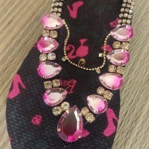 May include: Black flip-flops with a pink Barbie logo and pink and clear rhinestone embellishments.
