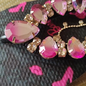 May include: A pink and clear crystal rhinestone flip flop strap with a gold chain detail.
