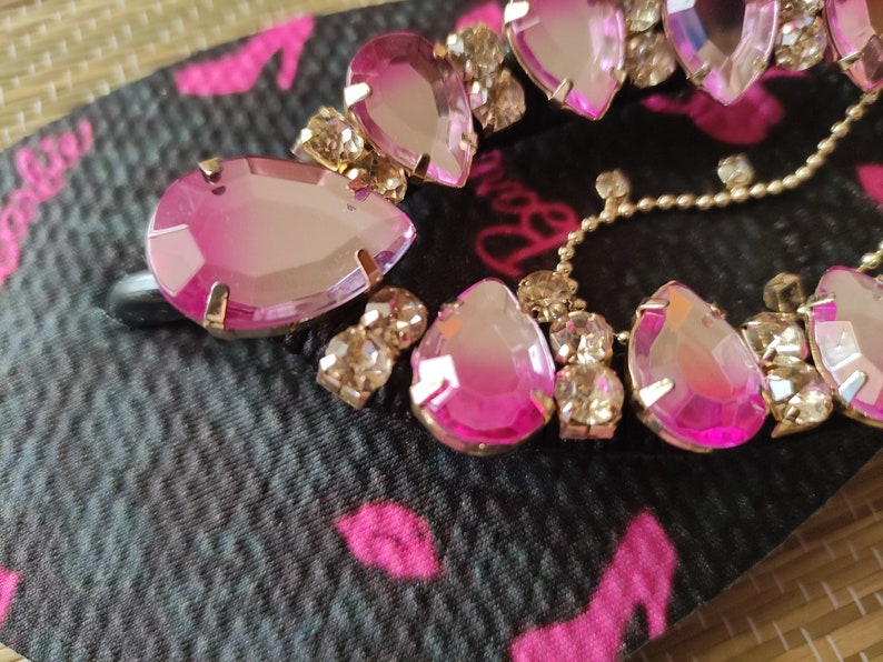 May include: A pink and clear crystal rhinestone flip flop strap with a gold chain detail.