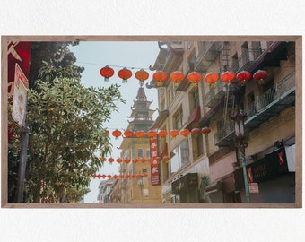 May include: A street in Chinatown, San Francisco, decorated with red lanterns. The street is lined with buildings, some with balconies and fire escapes. There are trees on either side of the street.