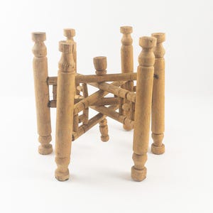 May include: A wooden folding table with a starburst design. The table is made of light brown wood and has six legs.