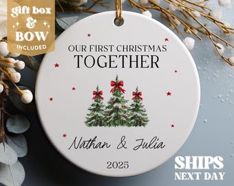 May include: White ceramic Christmas ornament with red stars and the text "Our First Christmas Together" with the names "Nathan & Julia" and the year "2025". The ornament features a watercolor illustration of three Christmas trees with red bows.