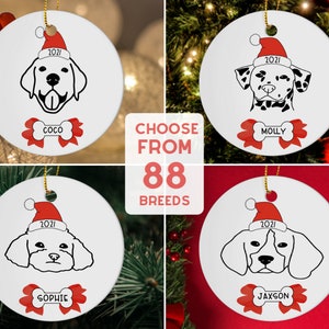 Pu&ograve; includere: Quattro addobbi natalizi in ceramica bianca con illustrazioni in bianco e nero di cani che indossano cappelli da Babbo Natale. Ogni addobbo ha un fiocco rosso con un osso al centro e un nome personalizzato sotto. Gli addobbi sono esposti su uno sfondo rosso e verde con il testo "CHOOSE FROM 88 BREEDS" e "FREE GIFT BOX WITH BOW".