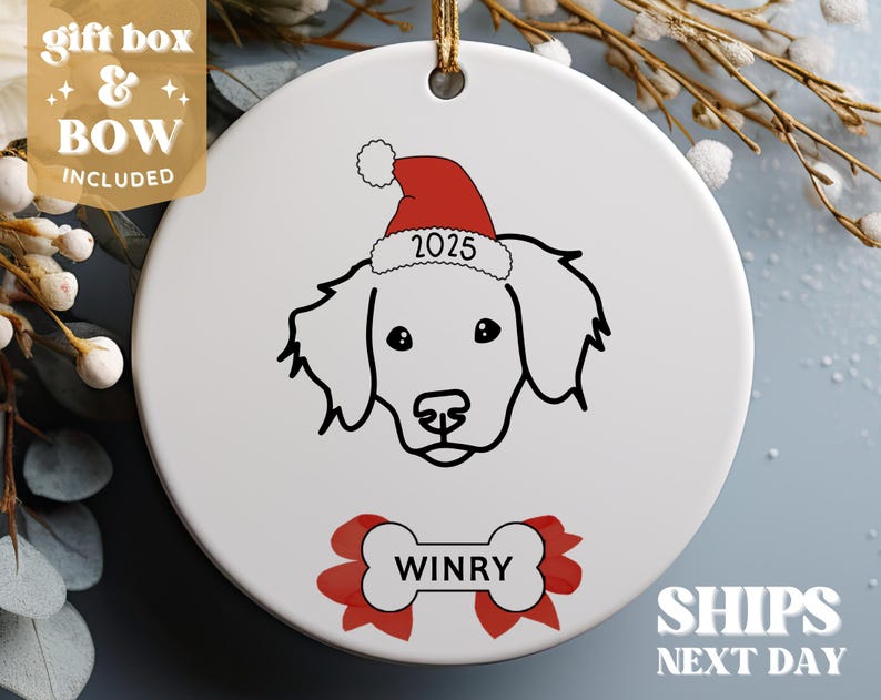 Pu&ograve; includere: Addobbo natalizio in ceramica bianca con un disegno a linea nera di un cane che indossa un cappello di Babbo Natale rosso con l'anno 2025. Il nome del cane, "WINRY", &egrave; scritto su un osso rosso e bianco.
