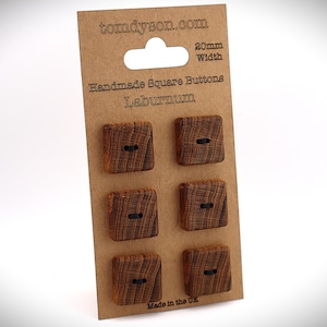 May include: A card of six handmade square Laburnum buttons. The buttons are a dark brown colour with a square shape and a black thread detail. The card has the text "tomdyson.com" and "20mm Width".