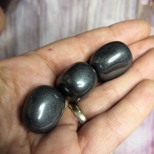 Peut inclure: Trois pierres lisses en hématite noire, roulées, avec une finition brillante et métallique.