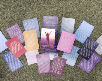 May include: A set of prayer cards with a variety of colors and designs. The cards feature different prayers and affirmations. The cards are arranged in a circle around a card with a woman standing on a mountain top with her arms raised. The card reads "Trust in the Lord Card Assortment".