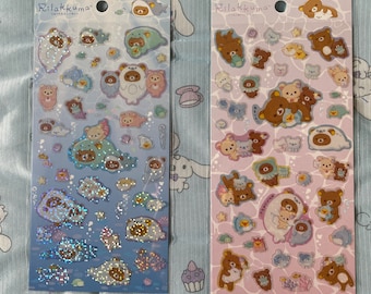 May include: Two sheets of Rilakkuma character stickers. The stickers are on a blue and pink background with a sea theme. The stickers feature Rilakkuma and his friends in various poses, including swimming, holding seashells, and riding seahorses. The stickers are perfect for adding a touch of cuteness to your planner, journal, or laptop.
