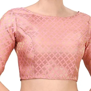 Könnte beinhalten: Eine rosa Brokatbluse mit quadratischem Muster und kurzen Ärmeln. Die Bluse hat einen runden Ausschnitt.