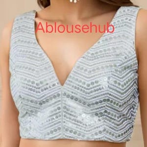 Puede incluir: Una blusa sin mangas de lentejuelas plateadas con un escote en V profundo. La blusa tiene un patr&oacute;n de chevron y est&aacute; hecha de una tela suave y c&oacute;moda.