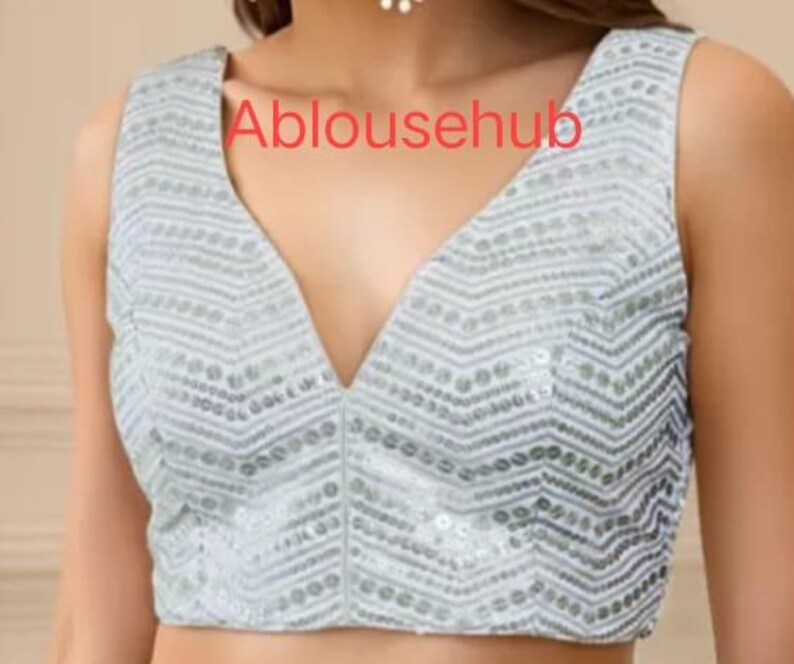 Puede incluir: Una blusa sin mangas de lentejuelas plateadas con un escote en V profundo. La blusa tiene un patr&oacute;n de chevron y est&aacute; hecha de una tela suave y c&oacute;moda.