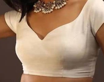 Puede incluir: Una blusa blanca sin mangas con un escote en V profundo y un corpiño ajustado.