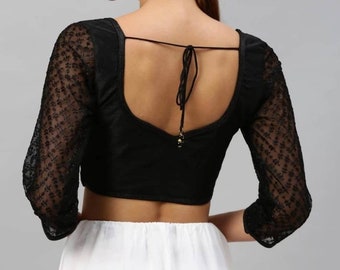 Könnte beinhalten: Schwarze ärmellose Bluse mit tiefem Rücken und durchsichtigen, bestickten Ärmeln.