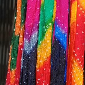 May include: A collection of colorful tie-dye scarves hanging on a clothesline. The scarves are made of a soft, flowing fabric and feature a variety of vibrant colors, including orange, red, green, blue, and purple. The scarves are decorated with a white tie-dye pattern.