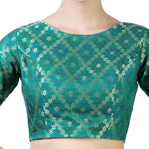 Peut inclure: Un chemisier bleu sarcelle à motif floral et accents dorés. Le chemisier a un col rond et des manches courtes.