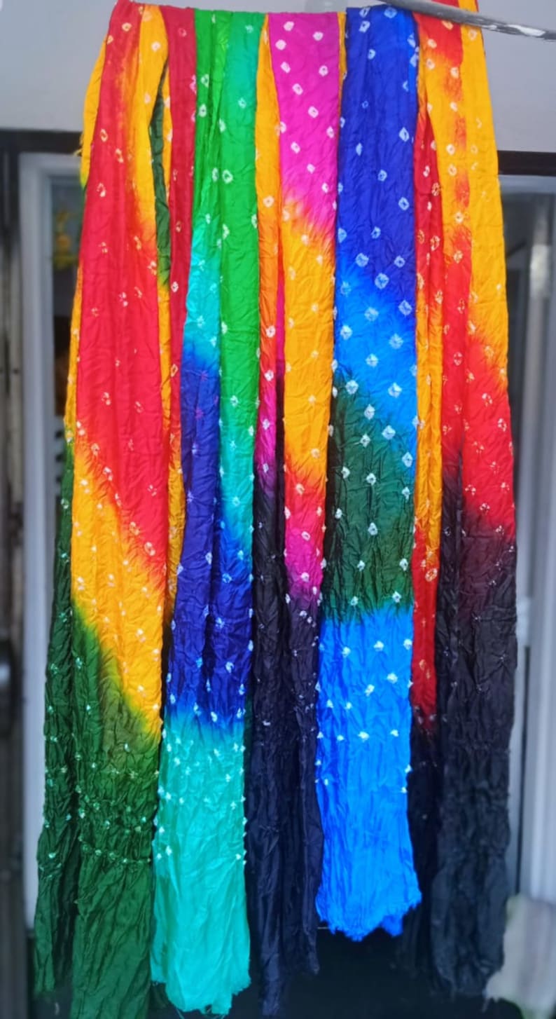 May include: A collection of eight colorful tie-dye scarves with white polka dots. The scarves are arranged in a row and are hanging from a metal rod.
