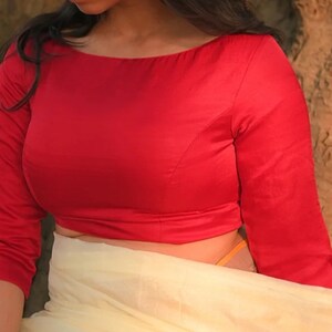 Peut inclure: Un chemisier rouge ajusté à manches longues et à col bateau.