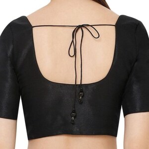 K&ouml;nnte beinhalten: Schwarze Bluse mit quadratischem Ausschnitt und kurzen &Auml;rmeln. Der R&uuml;cken hat einen Bindverschluss mit dekorativen Perlen. Der Stoff hat einen dezenten Glanz. Ein klassisches Kleidungsst&uuml;ck f&uuml;r verschiedene Anl&auml;sse.