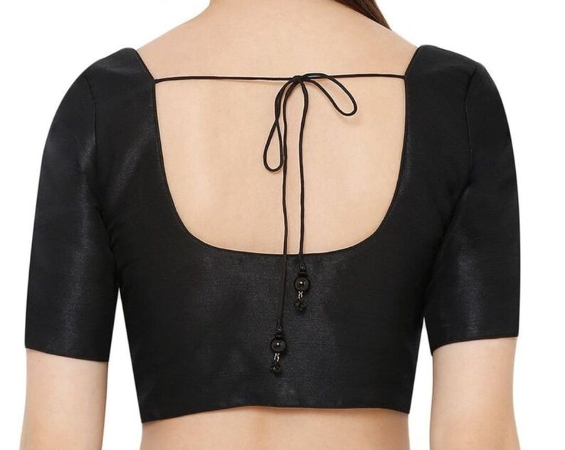 K&ouml;nnte beinhalten: Schwarze Bluse mit quadratischem Ausschnitt und kurzen &Auml;rmeln. Der R&uuml;cken hat einen Bindverschluss mit dekorativen Perlen. Der Stoff hat einen dezenten Glanz. Ein klassisches Kleidungsst&uuml;ck f&uuml;r verschiedene Anl&auml;sse.