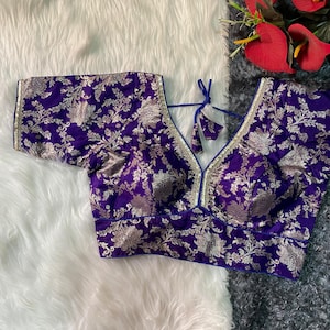 May include: A purple and gold brocade blouse with a blue trim and a tie at the neck.