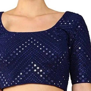 Puede incluir: Una blusa azul marino con un patrón geométrico y lentejuelas plateadas.