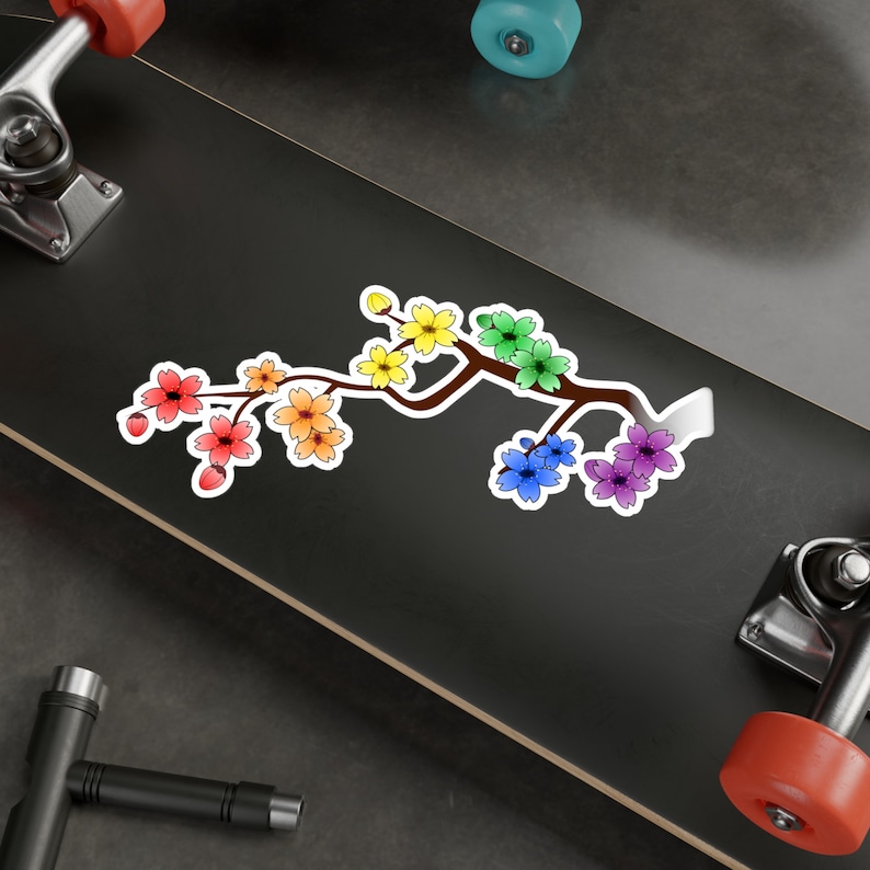 Pu&ograve; includere: Un adesivo di ramo di ciliegio in fiore arcobaleno con uno stelo marrone e un contorno bianco. I fiori sono disposti in linea lungo il ramo, con i colori che passano dal giallo al rosso.