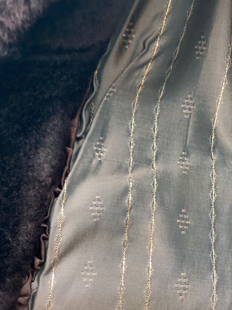 May include: Close-up of a dark brown fabric with a green fabric lining. The lining has a repeating diamond pattern and thin gold stripes.