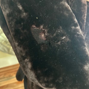 May include: A close-up of a brown faux fur jacket with a small hole in the fabric.