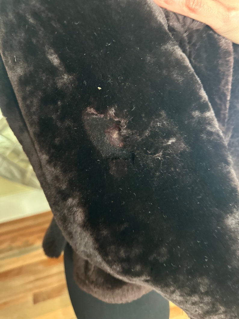 May include: A close-up of a brown faux fur jacket with a small hole in the fabric.