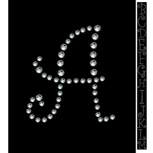 Könnte beinhalten: Ein silberner Strass-Buchstabe A mit einem dekorativen Wirbel auf der linken Seite. Der Buchstabe befindet sich auf einem schwarzen Hintergrund. Das Bild zeigt auch eine Spalte mit Buchstaben von A bis M in Strass.
