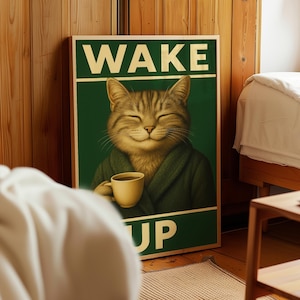 May include: A framed poster with a green background and the words "WAKE UP" in gold lettering. The poster features a smiling tabby cat wearing a green robe and holding a coffee cup. The poster is displayed in a bedroom setting.