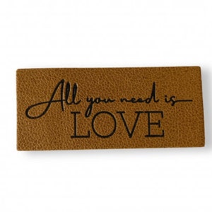 May include: A brown leather tag with the text "All you need is LOVE" embossed in black.