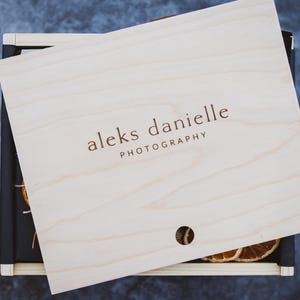 May include: A wooden box with a lid that has the text "aleks danielle PHOTOGRAPHY" printed on it. The box is open and there are dried orange slices inside.