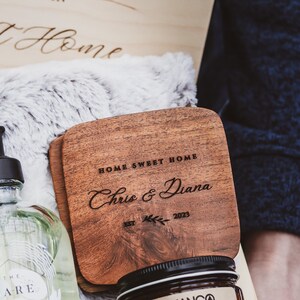 Puede incluir: Un posavasos de madera con el texto "Home Sweet Home" y "Chris & Diana" grabado en &eacute;l. El posavasos tambi&eacute;n tiene el texto "Est. 2023" y un peque&ntilde;o dise&ntilde;o de hoja.