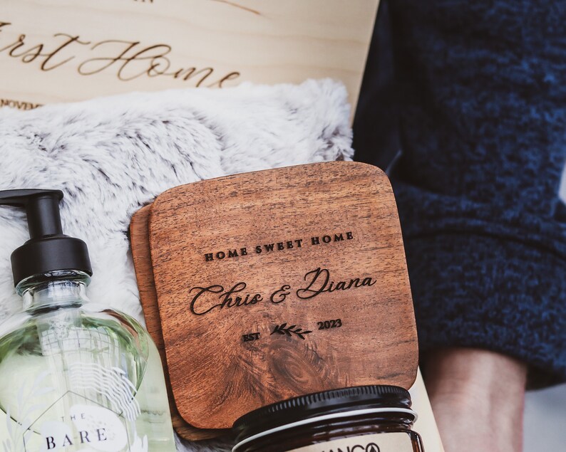Puede incluir: Un posavasos de madera con el texto "Home Sweet Home" y "Chris & Diana" grabado en &eacute;l. El posavasos tambi&eacute;n tiene el texto "Est. 2023" y un peque&ntilde;o dise&ntilde;o de hoja.