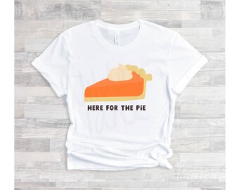 Puede incluir: Camiseta blanca con un gráfico de una rebanada de pastel de calabaza con crema batida y el texto "Here for the Pie".