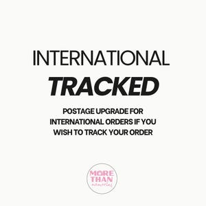 May include: White background with the words "INTERNATIONAL TRACKED" in bold black font. Below, smaller text reads "POSTAGE UPGRADE FOR INTERNATIONAL ORDERS IF YOU WISH TO TRACK YOUR ORDER." A circular logo with the words "MORE THAN memories" is at the bottom.