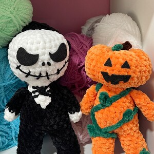 May include: Two handmade crochet dolls: Jack Skellington in black and white, and a pumpkin character in orange and green. The dolls are displayed in a white shelf with colorful yarn in the background. Perfect for Halloween decor.