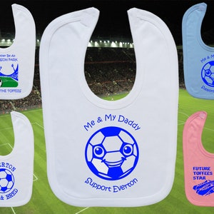 Puede incluir: Cuatro baberos de bebé blancos con diseños azules y blancos. Un babero tiene un balón de fútbol con una cara y el texto "Yo y mi papá apoyamos a Everton". Otro babero tiene un balón de fútbol y el texto "Everton nacido y criado". Un tercer babero tiene un balón de fútbol y el texto "Prefiero estar en Goodison Park viendo a los Toffees". El cuarto babero tiene un balón de fútbol y el texto "Yo y mi papá apoyamos a Everson".