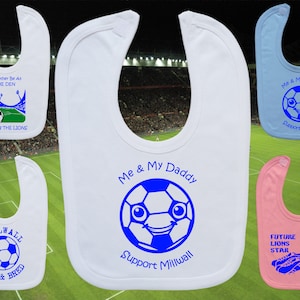 Pode incluir: Quatro babadores brancos para bebé com diferentes designs. Um babador tem uma bola de futebol azul com uma cara e o texto "Me & My Daddy Support Millwall". Outro babador tem uma bola de futebol azul com uma cara e o texto "Me & My Daddy Support Millwall". Outro babador tem uma bola de futebol azul com uma cara e o texto "Future Lions Star". O último babador tem uma bola de futebol azul com uma cara e o texto "I'd Rather Be At The Den Watching The Lions".