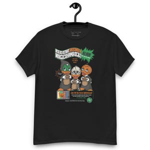 May include: Black t-shirt with a graphic of three cartoon ducks wearing Halloween costumes. The text "Not So Scary Halloween Magic Shamrock" is printed on the shirt.